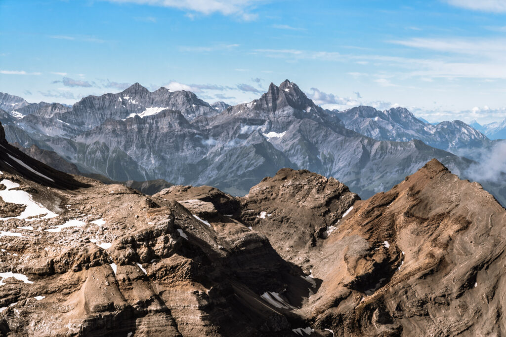 Breathtaking mountain landscape with snow-dusted rocks under blue sky and drifting clouds Wallpaper