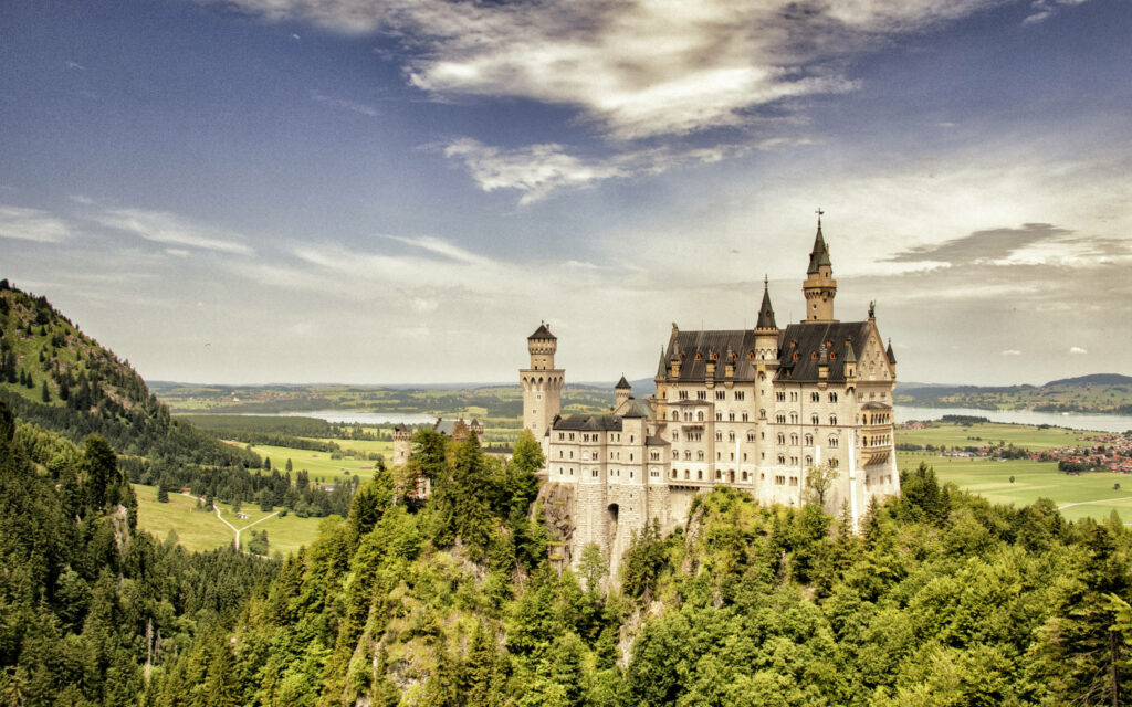 Breathtaking Neuschwanstein Castle Wallpaper: Lush Greenery & Clouds