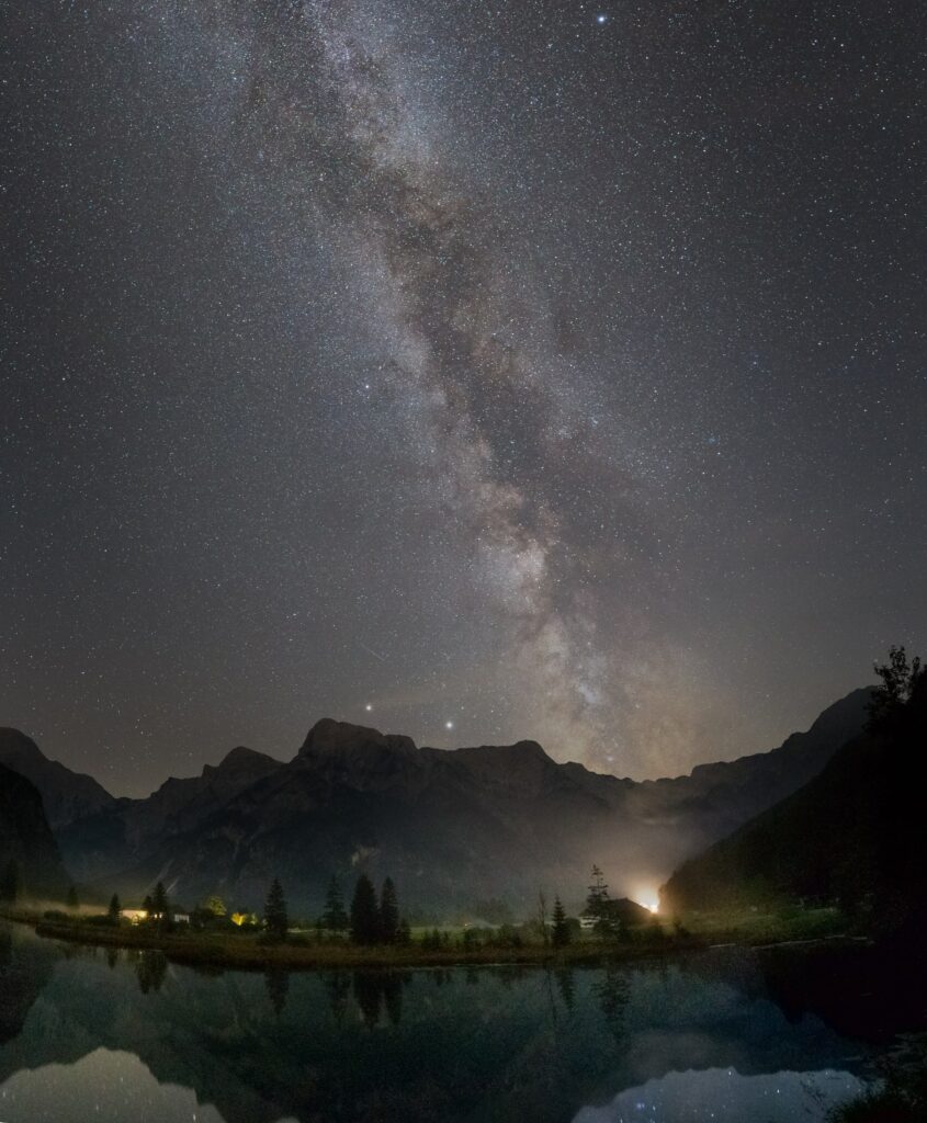 Breathtaking night sky with vibrant nebula stars shadowy mountains and calm reflective waters wallpaper