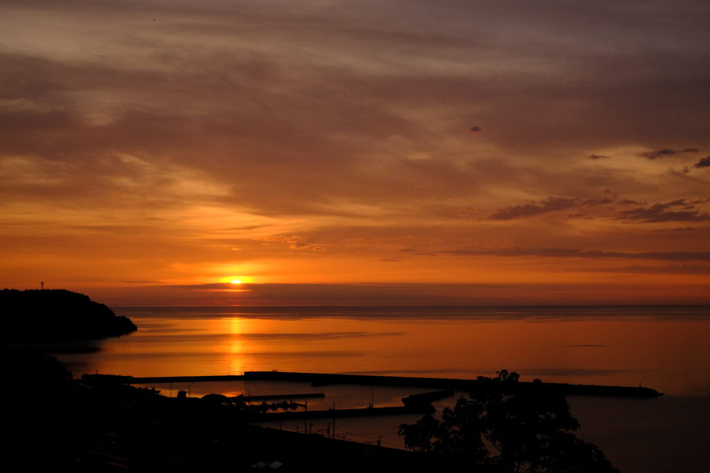 Sunset wallpaper with glowing orange gold sky calm sea reflecting warm light serene horizon view
