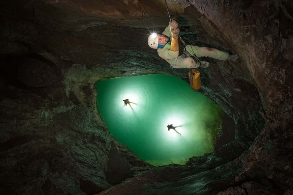 Adventurer Rappelling in Enchanting Cave with Crystal Clear Waters Wallpaper