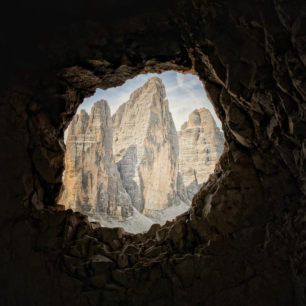 Rocky mountain view framed by cave entrance with textured stones and clear sky background wallpaper