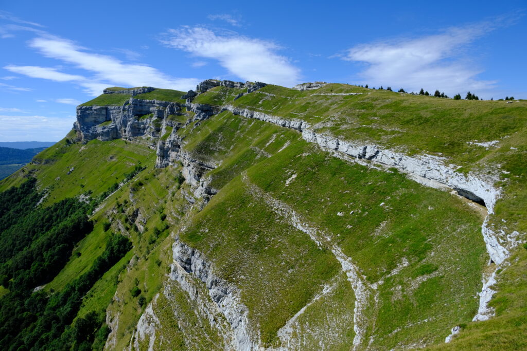 Breathtaking rugged rock cliffs with lush green trees under clear blue sky natural landscape wallpaper