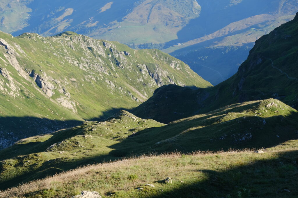 Breathtaking rugged mountains and rolling green hills with dramatic shadows in soft daylight wallpaper