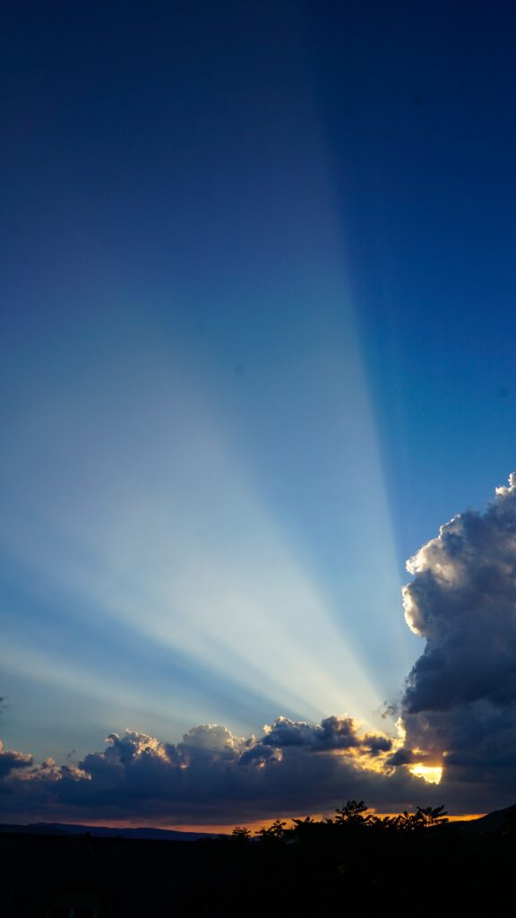 Breathtaking sky wallpaper with radiant sun rays through dramatic clouds over blue horizon