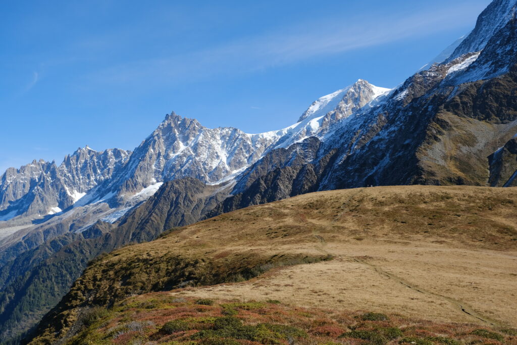 Breathtaking snow-capped mountain range with rugged peaks and dry grassy foreground landscape Wallpaper