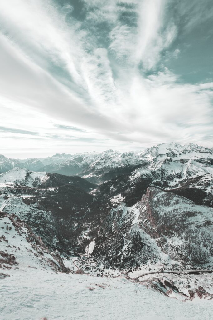 Aerial view of snow-covered Dolomites Italy winter mountains with dramatic peaks and cloudy sky Wallpaper