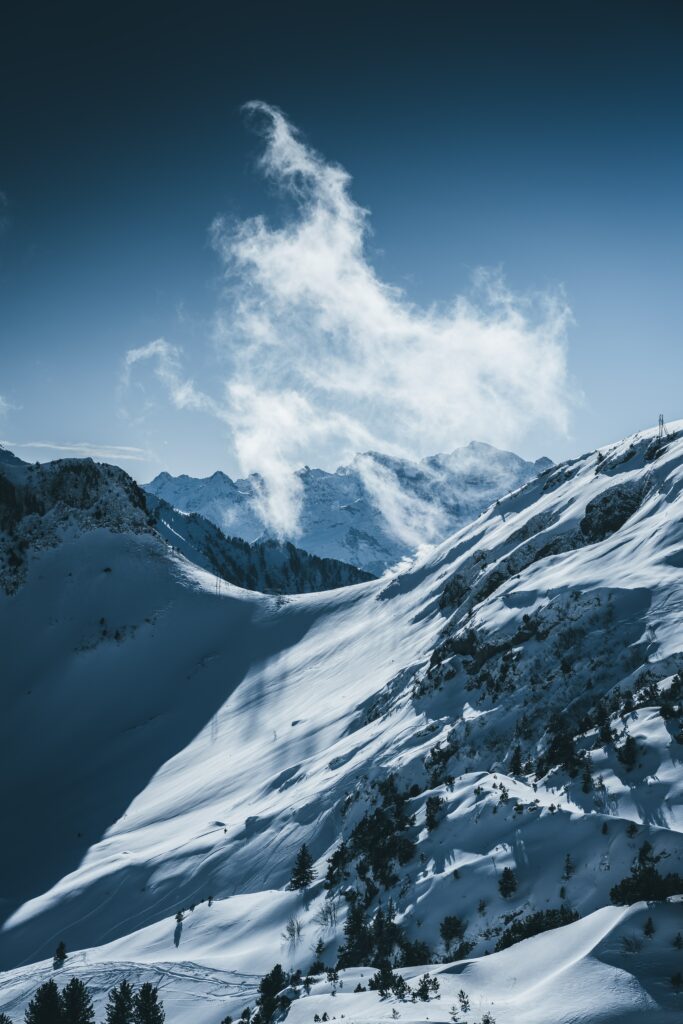Snowy mountain landscape winter wallpaper with clear blue sky dramatic clouds and sunlight shadows