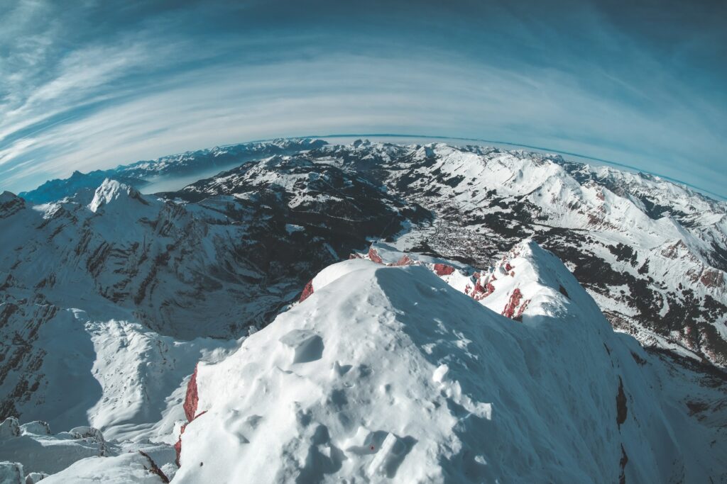 Snow-covered mountain peaks under clear winter sky with crisp whites and cool blue tones Wallpaper