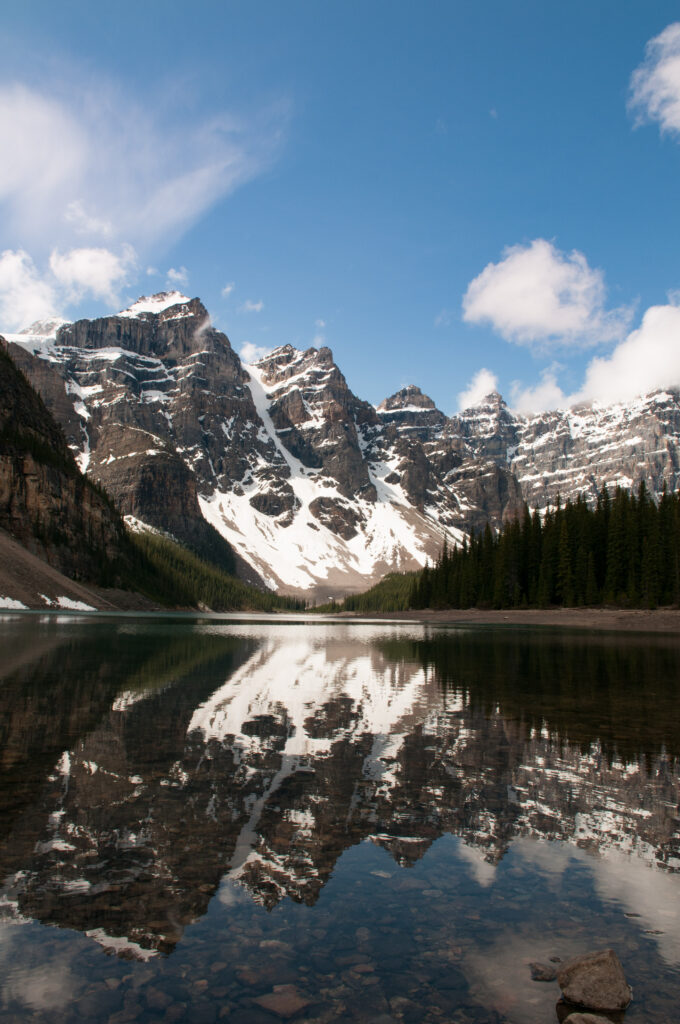 Snow-capped mountain peaks with green forest and clear lake reflecting bright blue sky wallpaper