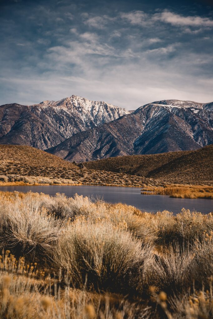 Breathtaking snowy mountain range reflected in calm lake with golden valley landscape wallpaper