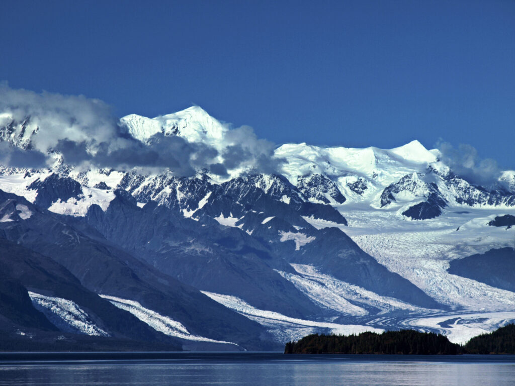 Snowy mountain landscape with glaciers serene blue sky and tranquil water in winter alpine scene Wallpaper