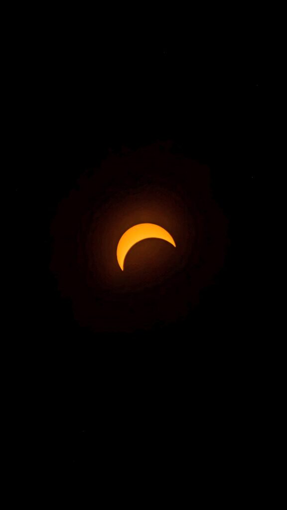 Solar eclipse through telescope showing crescent sun with orange glow on black background wallpaper