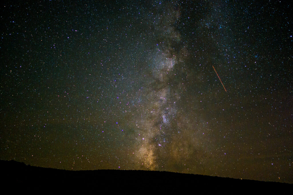 Starry night sky wallpaper with glowing Milky Way and shooting star showcasing vast space