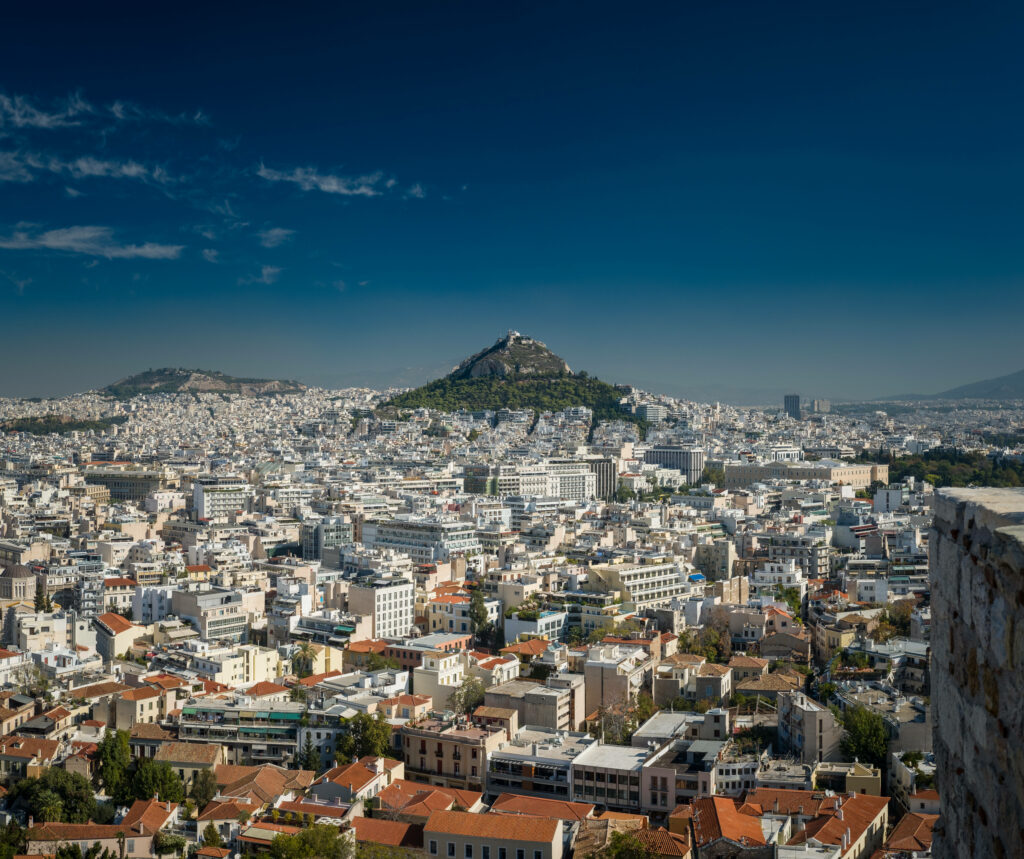 Stunning Sunlit Greek Cityscape Wallpaper: Whitewashed Buildings & Blue Sky