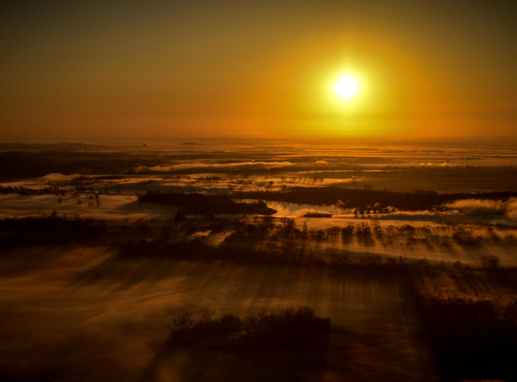 Aerial sunset view with golden hues and misty landscape casting long shadows at dusk wallpaper