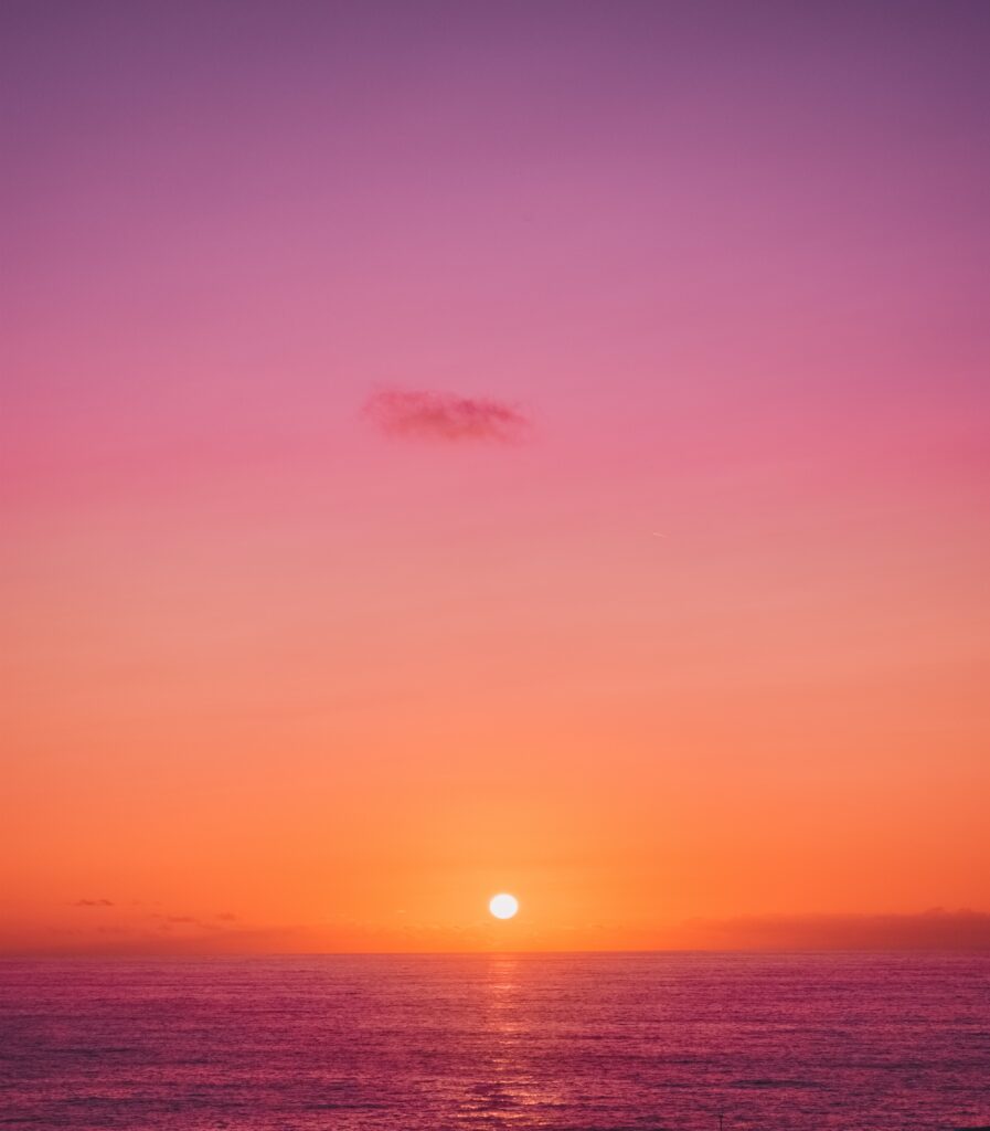 Sunset wallpaper with vibrant orange pink purple sky reflecting on calm ocean horizon background
