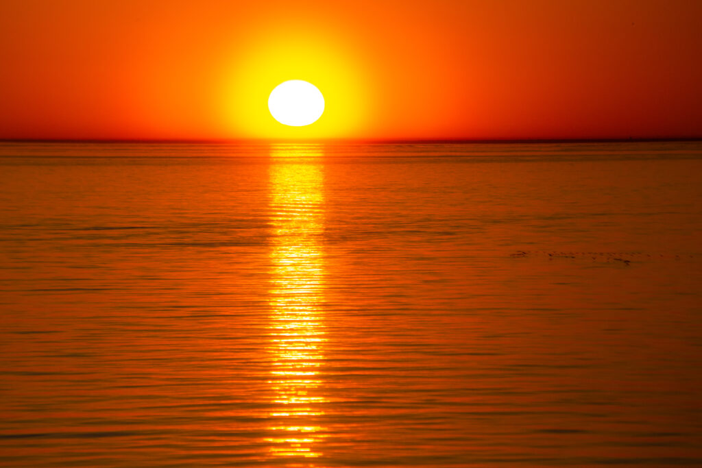 Breathtaking sunset over calm sea with golden sun reflection creating serene wallpaper background