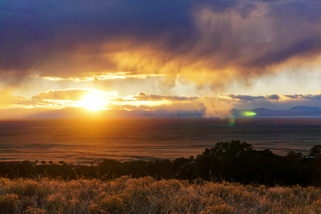Breathtaking sunset over mountains with vibrant orange yellow and blue sky and dramatic clouds Wallpaper