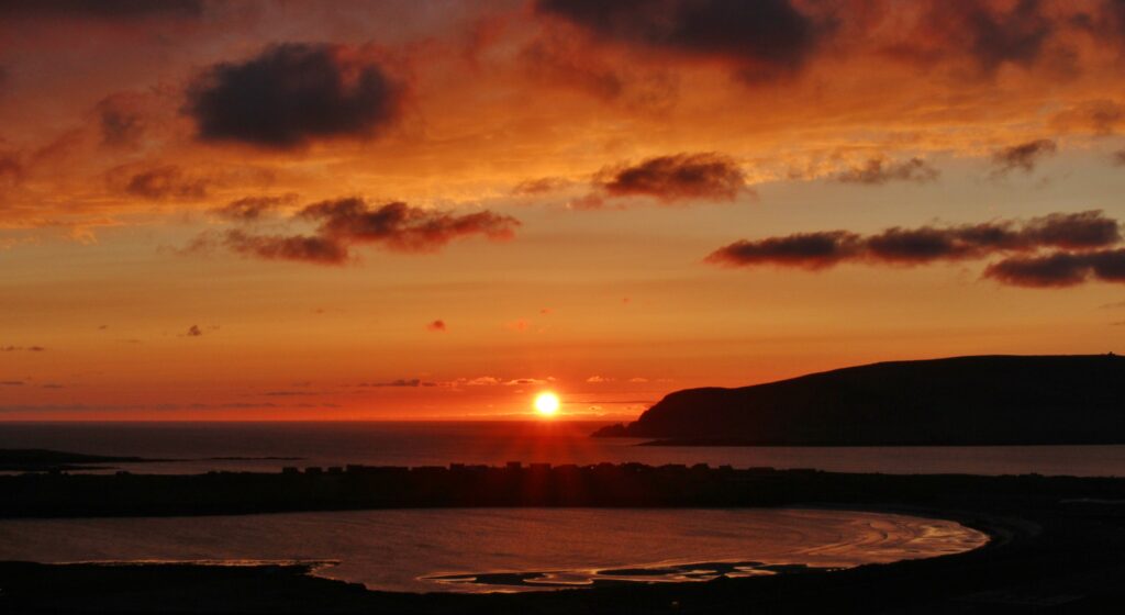 Breathtaking sunset over calm waters with golden rays and silhouetted hills wallpaper background