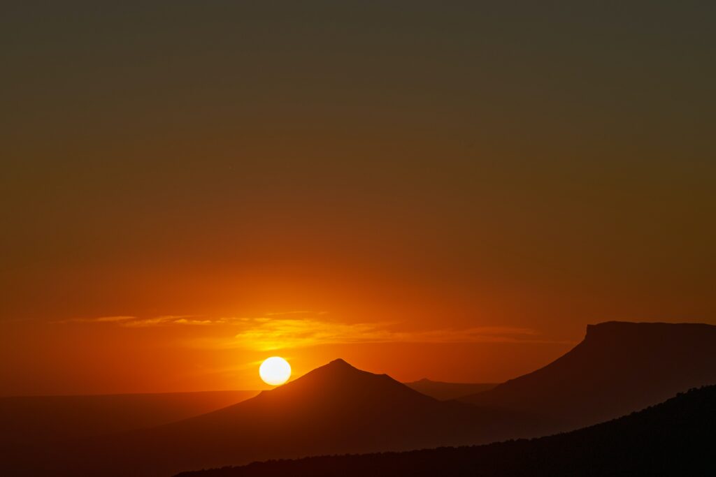Breathtaking sunset over rugged mountains with golden sky and dark landscape silhouettes wallpaper