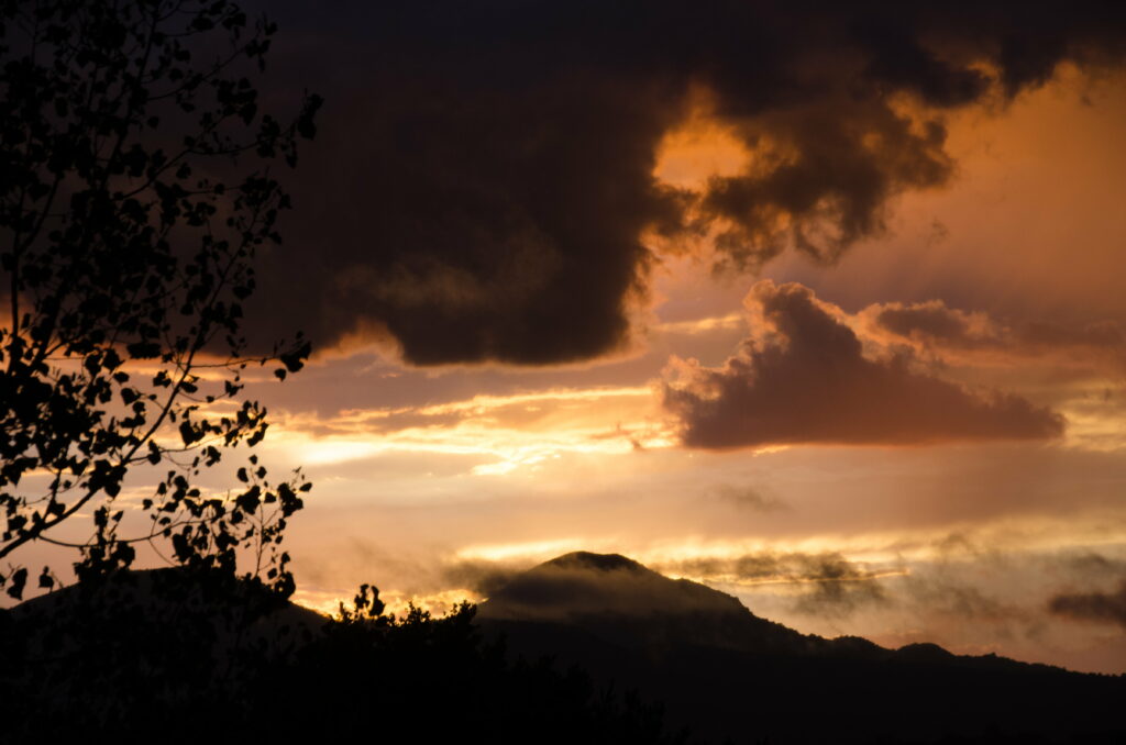 Breathtaking Sunset Over Hilly Landscape: Ethereal Clouds & Silhouettes Wallpaper