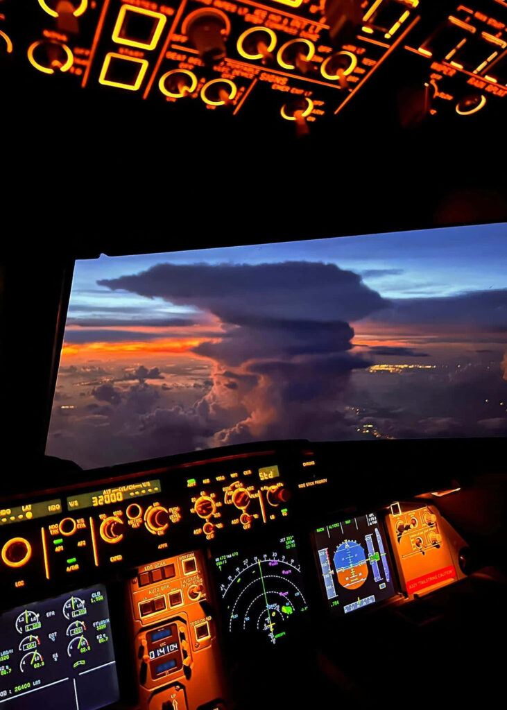 Sunset view from aircraft cockpit with orange blue sky clouds and illuminated control panels Wallpaper