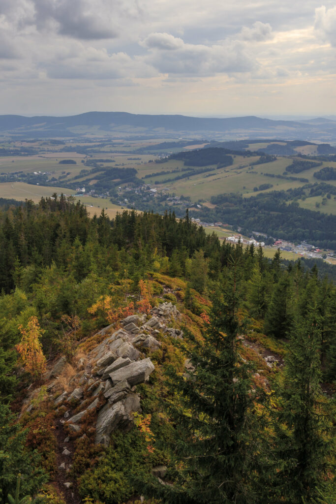 Breathtaking valley with rugged rocks vibrant trees lush green forests under dramatic cloudy sky wallpaper