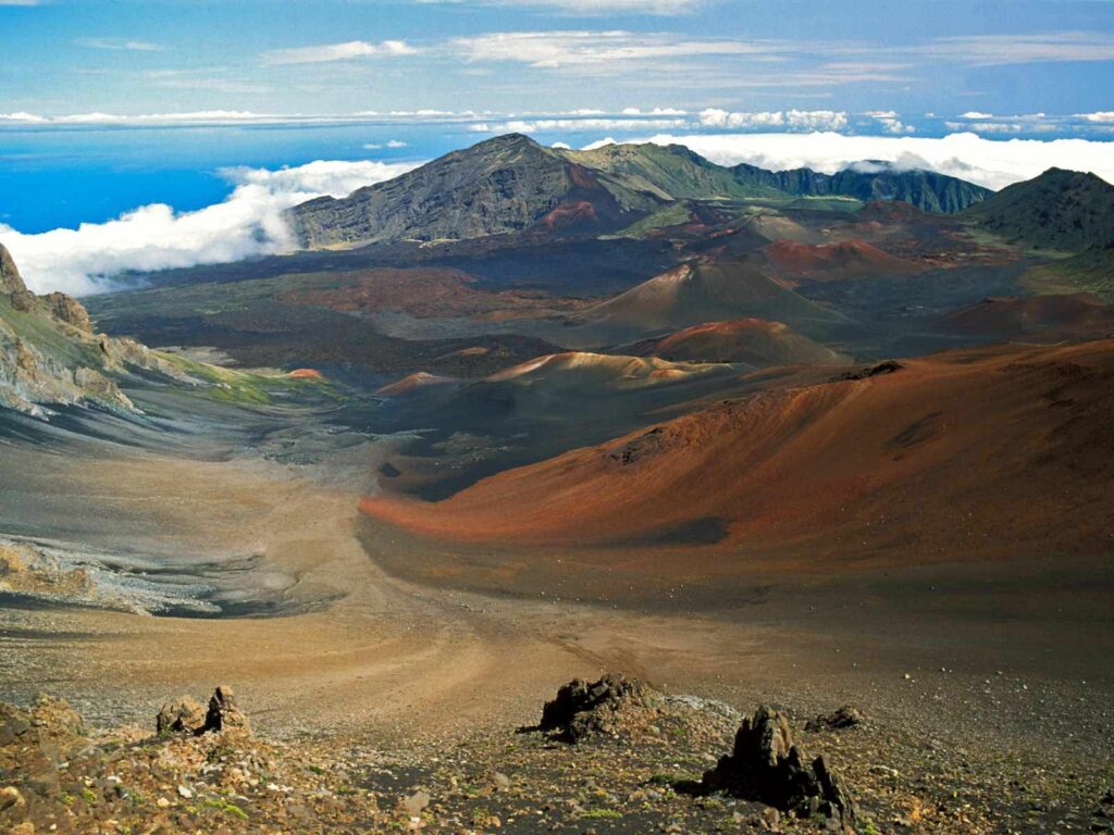 Breathtaking volcanic mountain landscape with rugged slopes clouds and clear blue sky wallpaper