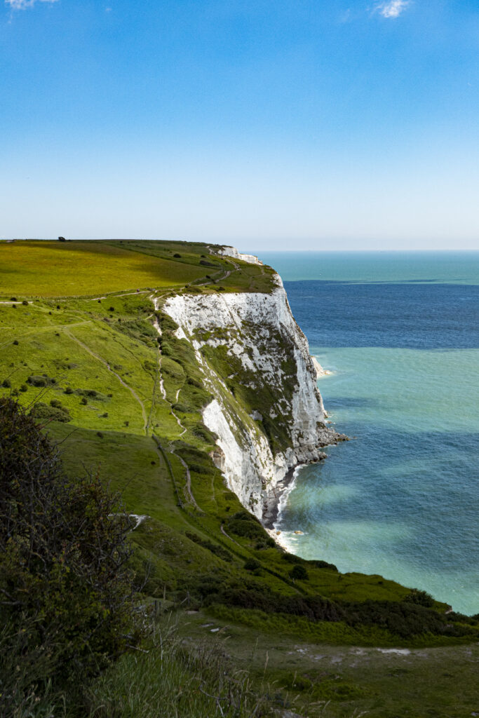 Breathtaking coastal wallpaper with white cliffs turquoise sea green cliffs under clear blue sky
