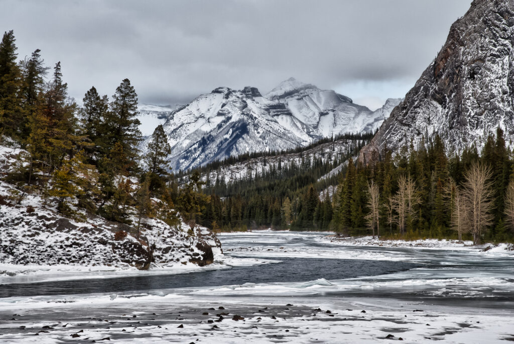Snow-covered mountains rocky cliffs icy lake evergreen trees winter landscape wallpaper background