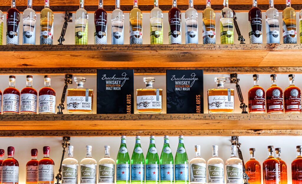 Colorful Breckenridge Distillery premium vodka gin bourbon bottles on rustic wooden shelves wallpaper