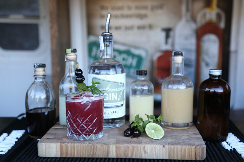 Breckenridge Distillery gin cocktail with fruit extracts mint lime cherries on rustic wood board Wallpaper
