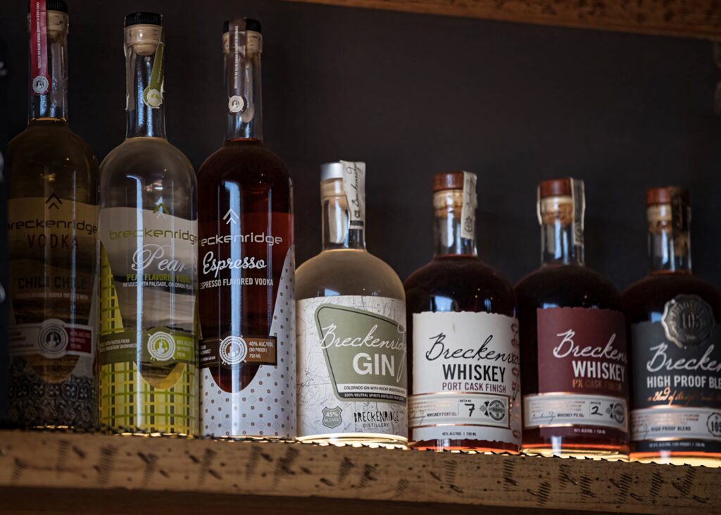 Premium Breckenridge Distillery spirits lineup on rustic shelves with warm ambient lighting Wallpaper
