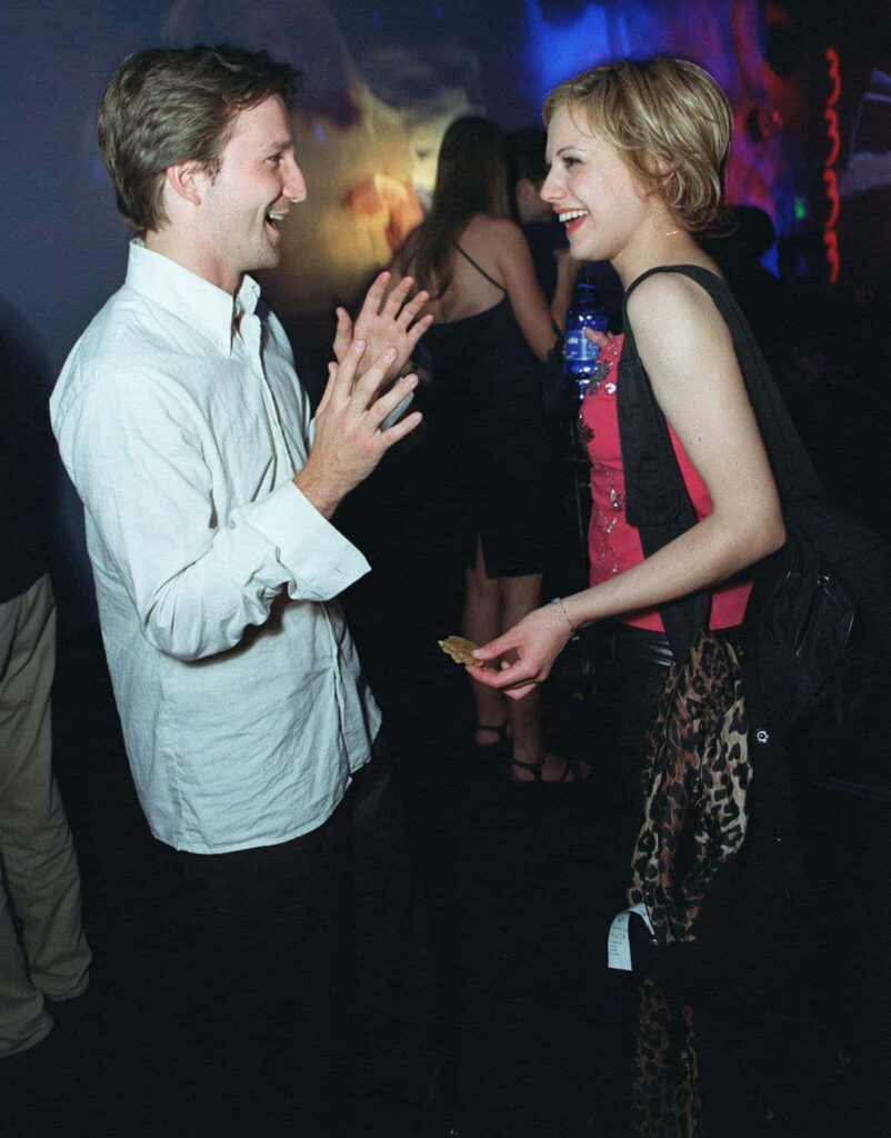 Breckin Meyer and Brittany Murphy candidly chatting at event vibrant backdrop stylish outfits wallpaper