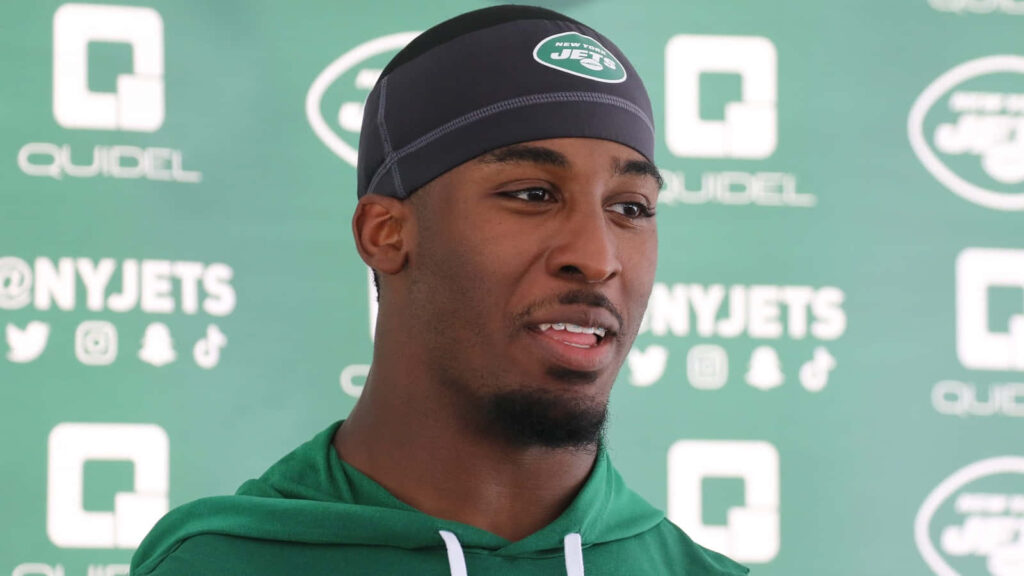 Breece Hall focused at New York Jets press conference with team green branding wallpaper background