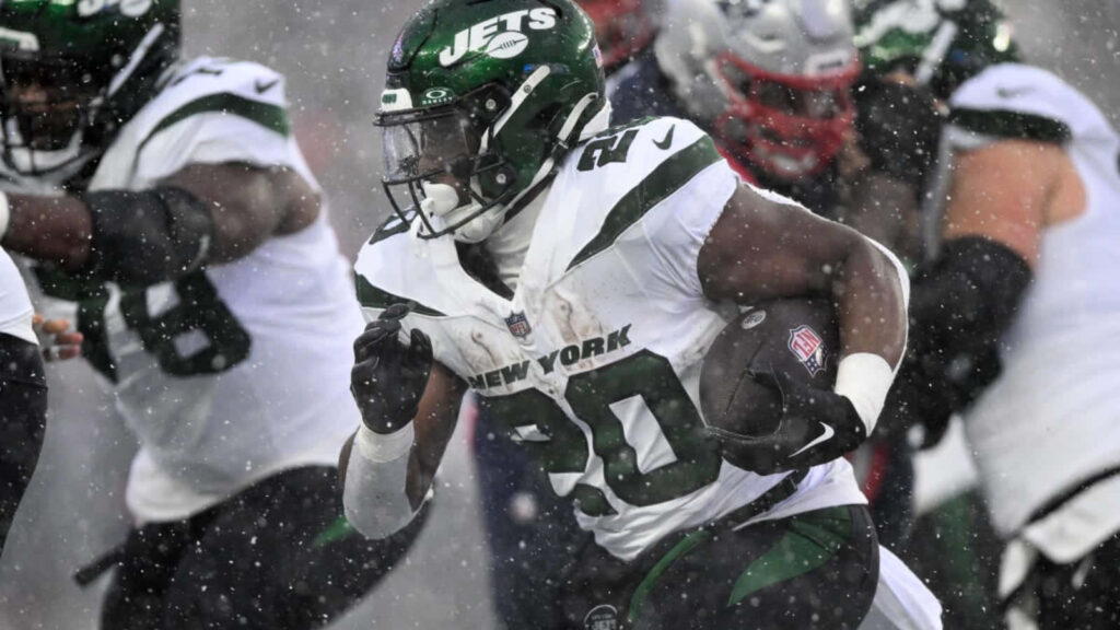 Breece Hall New York Jets action snow game wallpaper bold uniforms falling snow energetic play