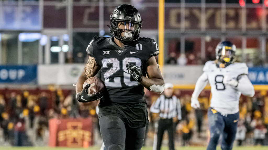 Breece Hall running back sprinting with football in black uniform high energy sports wallpaper