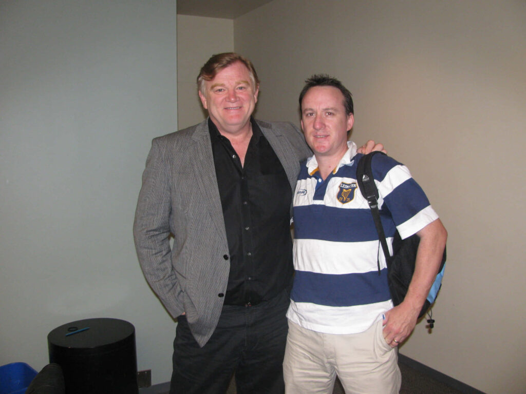 Brendan Gleeson smiling casually indoors with friend neutral background desktop wallpaper