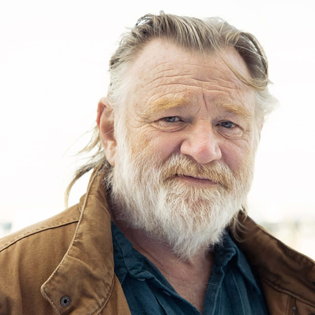 Brendan Gleeson portrait close-up with rugged beard brown jacket blue shirt soft blurred background Wallpaper