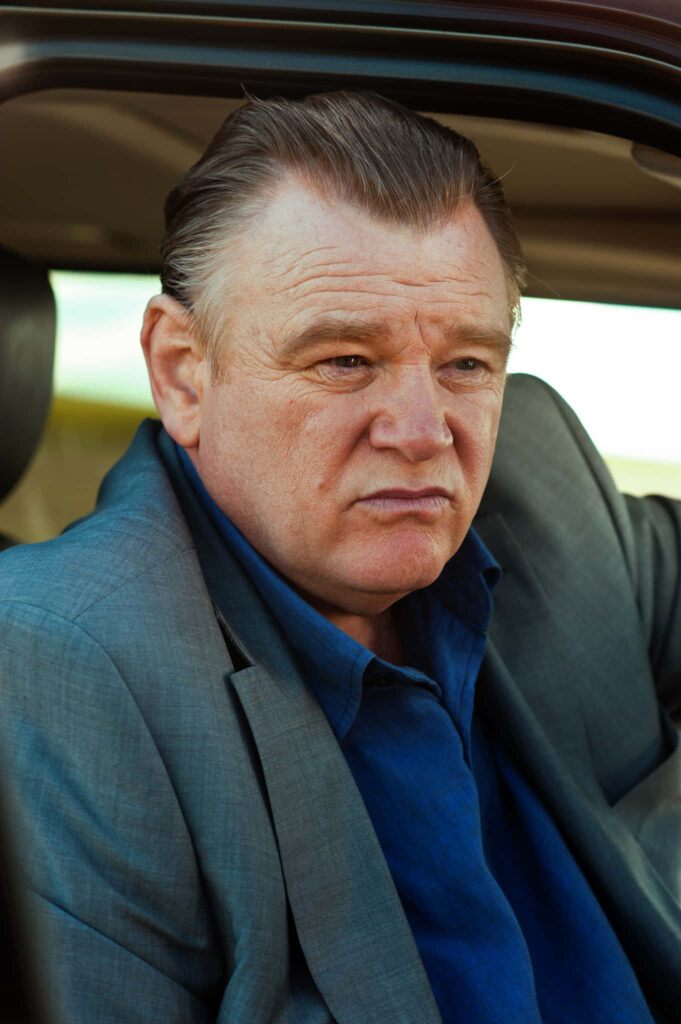 Close-up portrait of Brendan Gleeson seated in vehicle natural light classic attire wallpaper