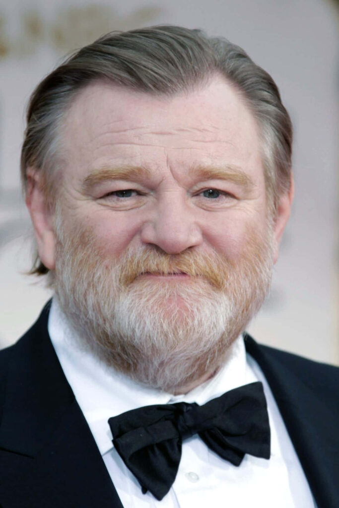 Brendan Gleeson close-up portrait in black tuxedo with distinguished beard and neutral background Wallpaper