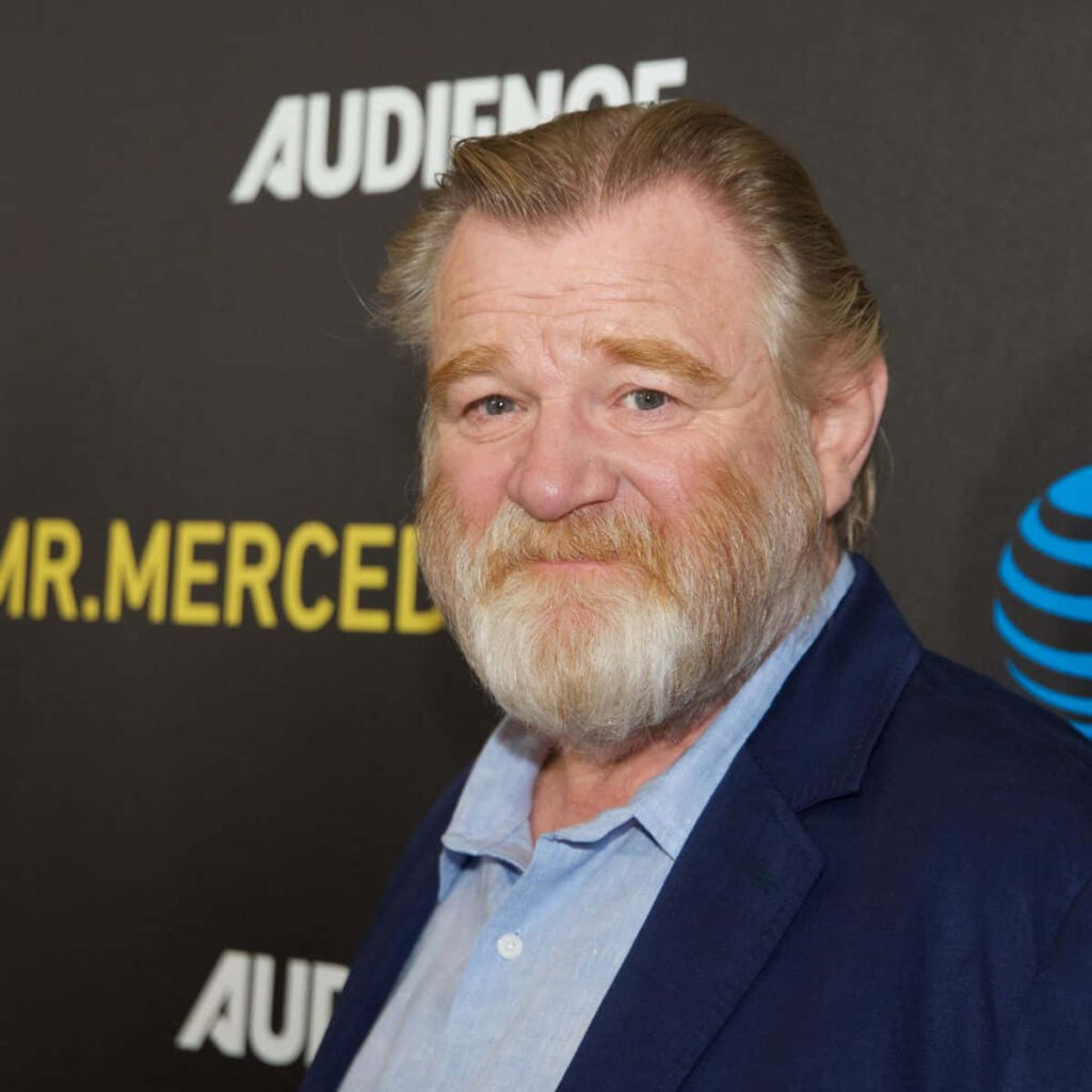 Brendan Gleeson portrait in blue blazer on black background with bold yellow and white text Wallpaper