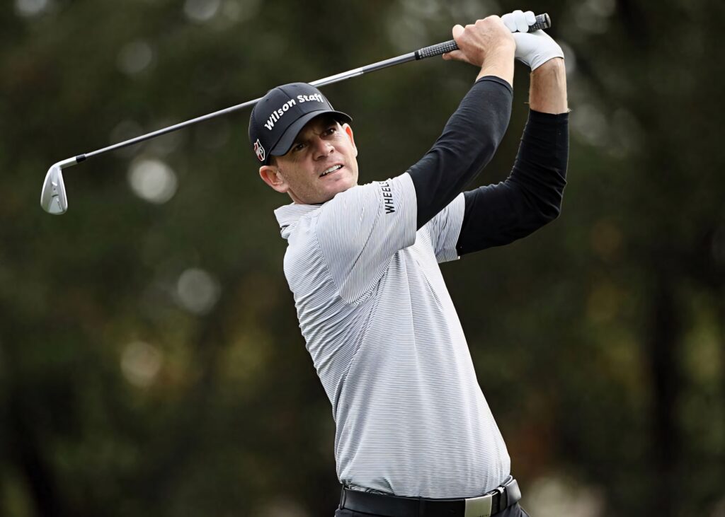 Brendan Steele mid-swing in gray golf outfit focused on ball with blurred natural golf course background Wallpaper