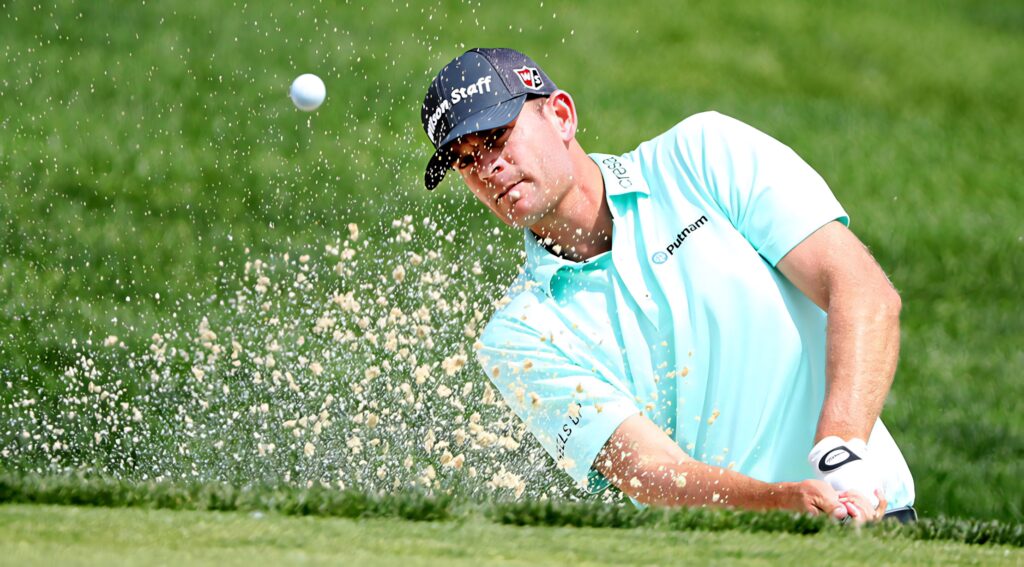 Brendan Steele golf swing from sand bunker with flying sand vibrant green grass background Wallpaper