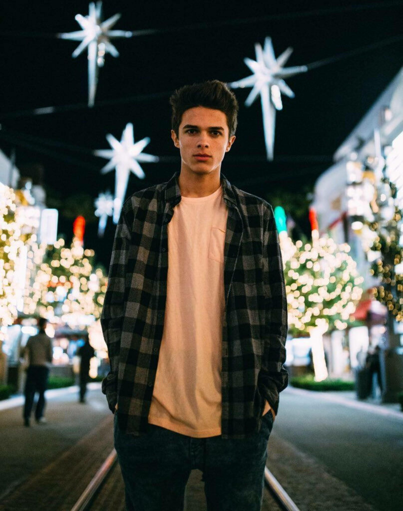 Brent Rivera on vibrant night street with glowing lights star decorations and illuminated trees Wallpaper