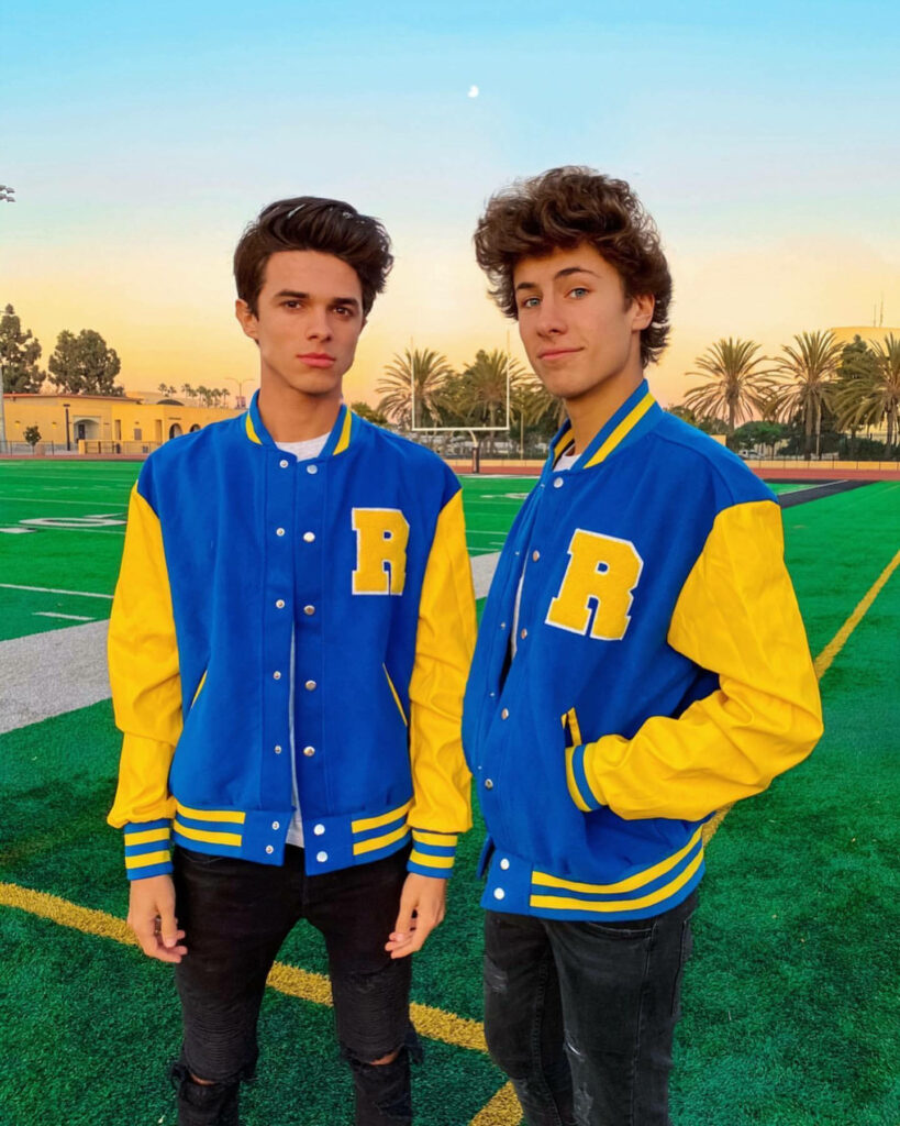 Brent Rivera and Ben Azelart varsity jackets on green field sunset palm trees vibrant wallpaper