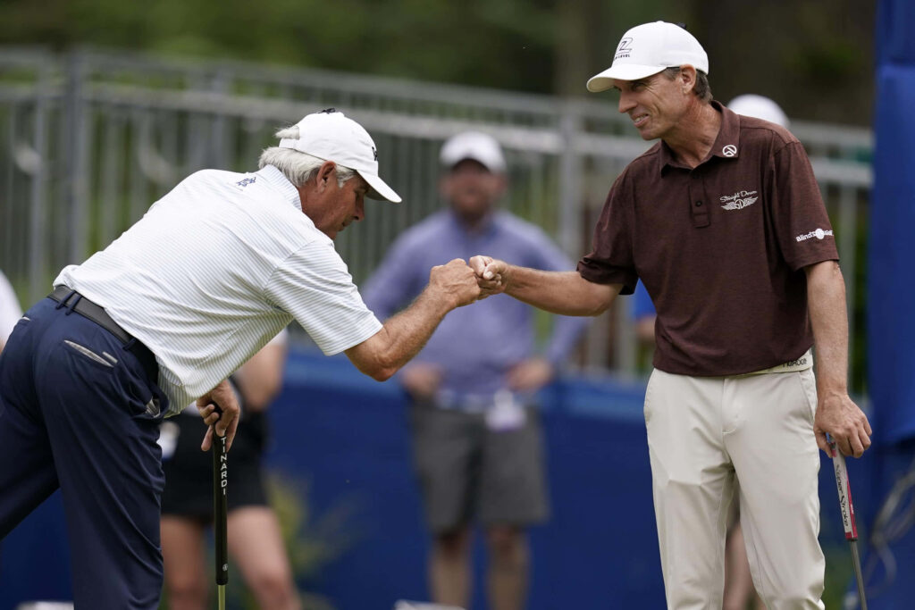 Brett Quigley fist bumps golfer on lush green golf course showing sportsmanship tournament Wallpaper