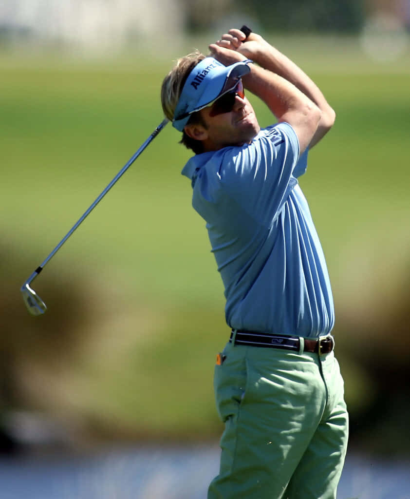 Brett Quigley golfer portrait on green course in blue polo and visor focused post-swing stance Wallpaper