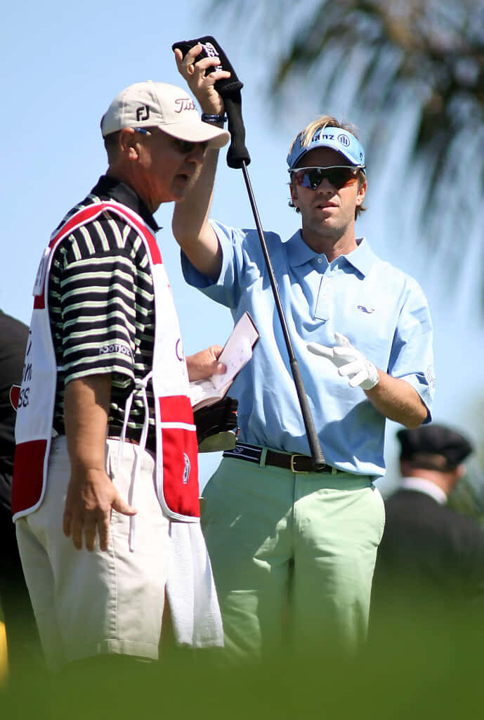 Brett Quigley and caddie on sunny golf course showing teamwork and focus in pro golf game Wallpaper